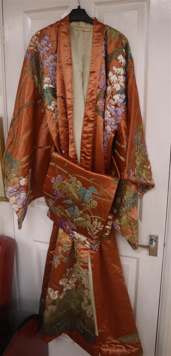 An early 20th century peach silk Japanese kimono, embroidered with polychrome silks of trailing wisteria and a similar obi